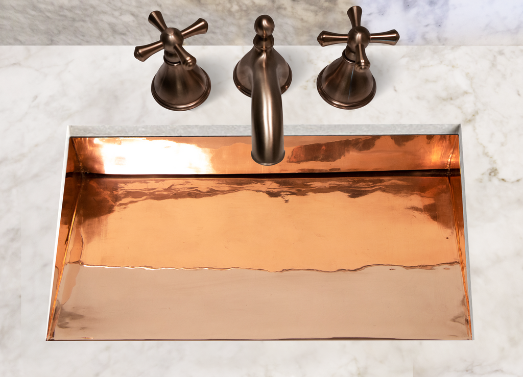 Copper sink with faucet on a marble countertop